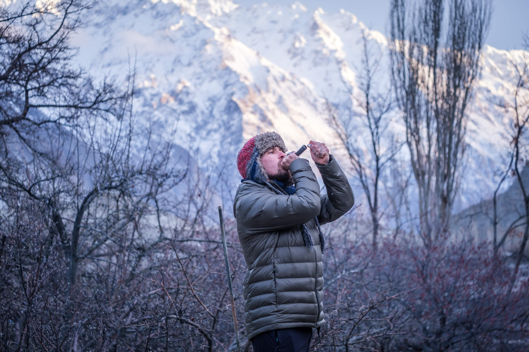 man smoking a chillum of hash in pakistan with a massive snow covered mountain in the distance