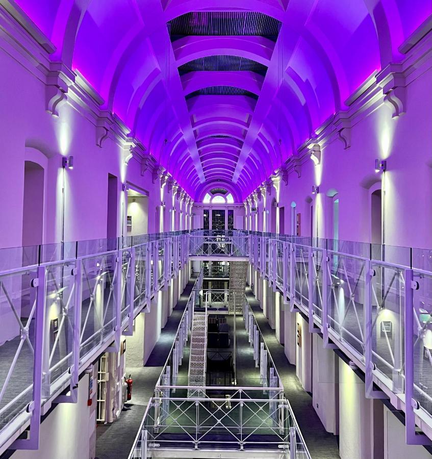 Brightly lit hallway with purple lighting at Malmaison prison hotel, UK