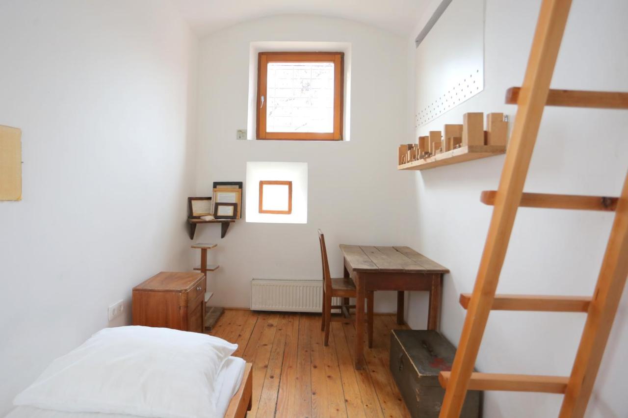 small prison hotel room with white walls and wooden furnishings in The Celica Hostel - Ljubljana, Slovenia