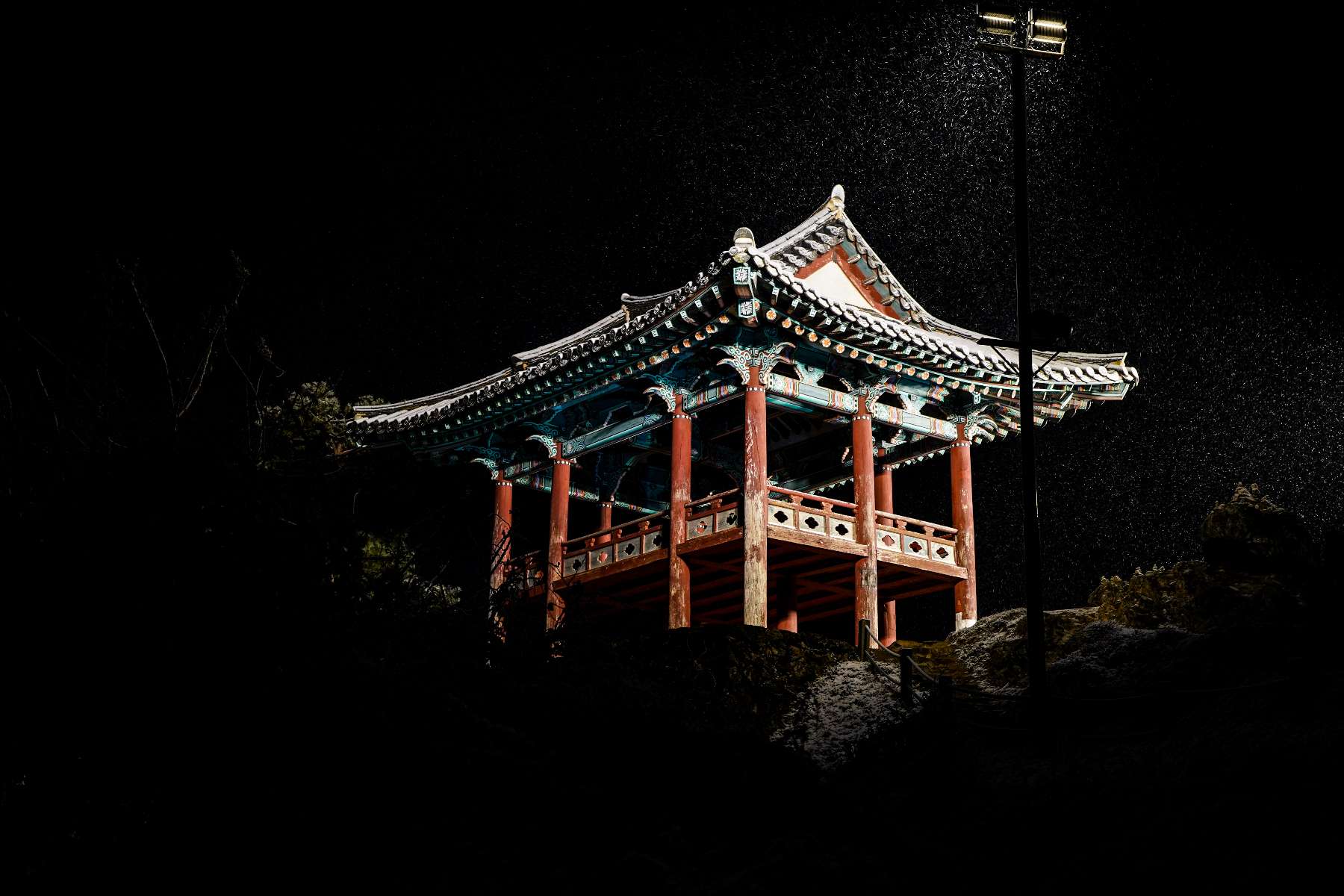 a traditional structure in south korea in the dark being coated in snow