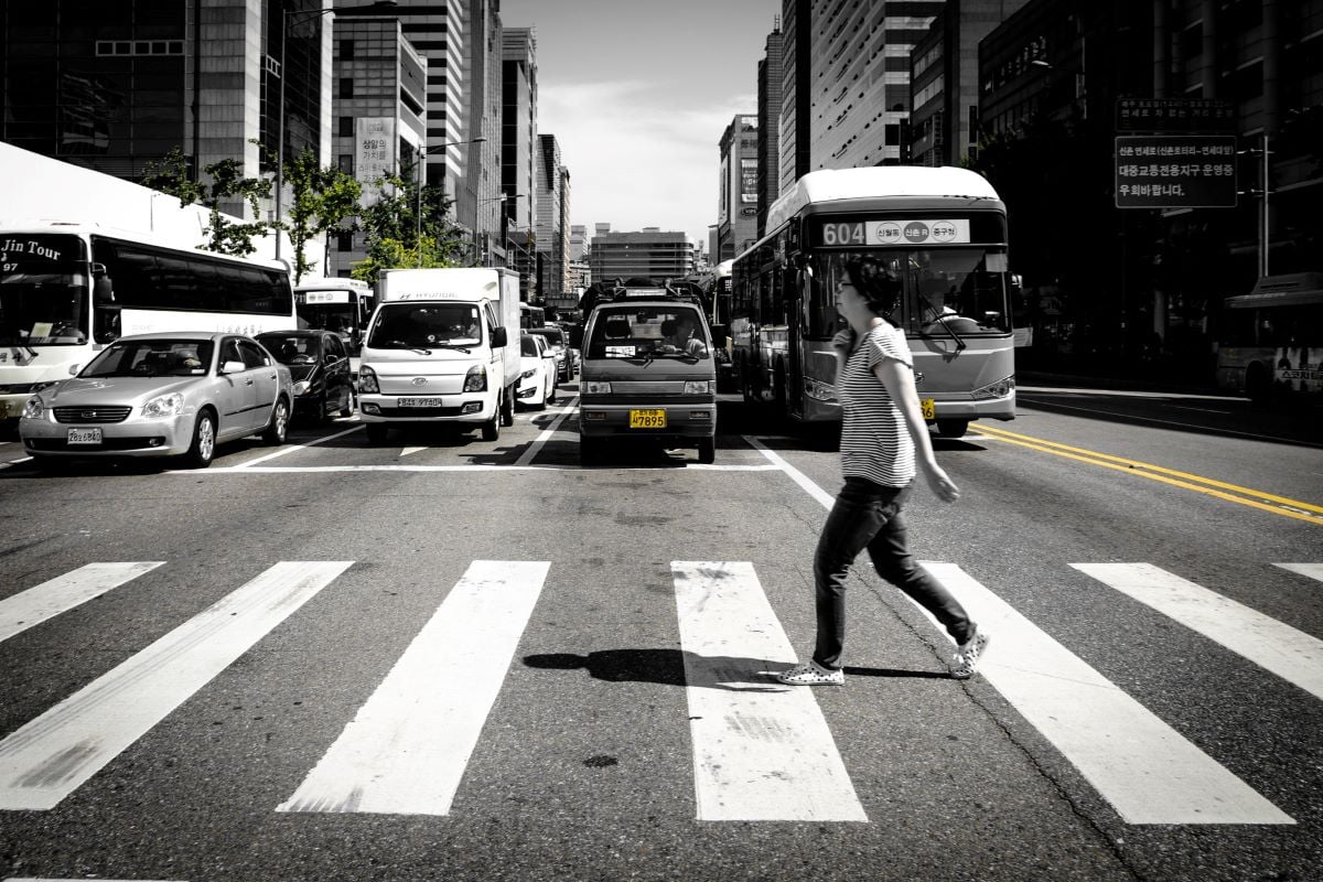 a person crossing a crosswalk on a busy street in seoul south korea