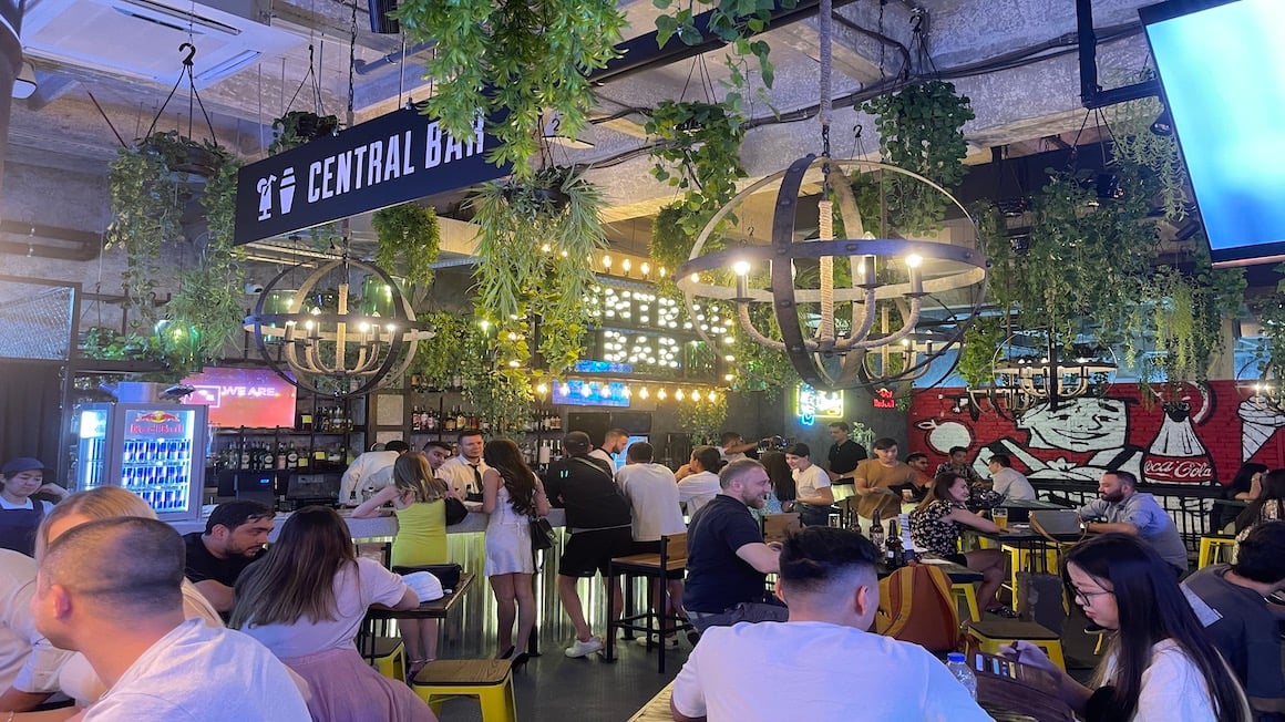 people sitting at tables at large open air bar in tashkent uzbekistan that's filled with numerous lush hanging plants