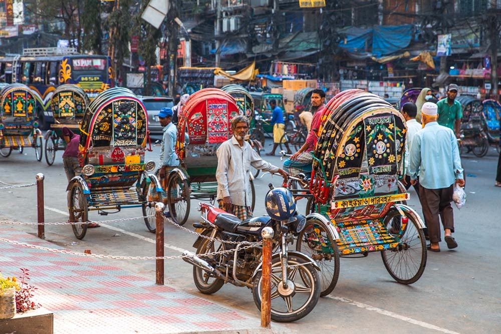 men standing with colorful bicycle rickshaws in chittagong bangladesh