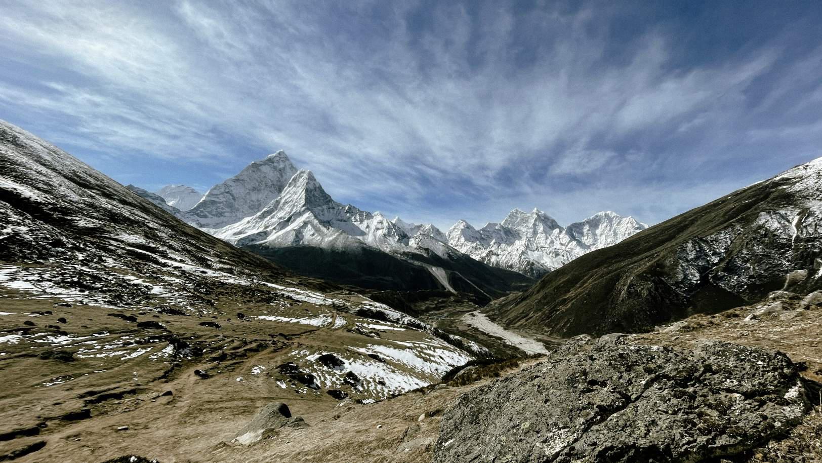 white himalayan mountains rising up above a wide expanse of brown glacial rock in nepal