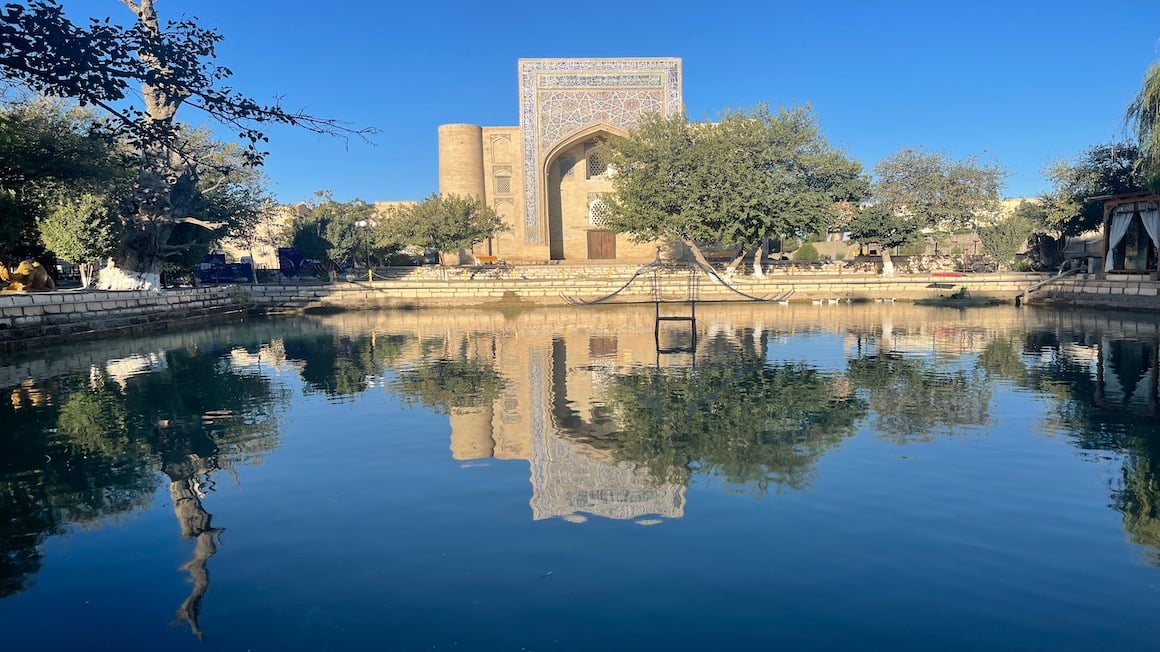 reflection of a historical mosque in a small pond in bukhara uzbekistan