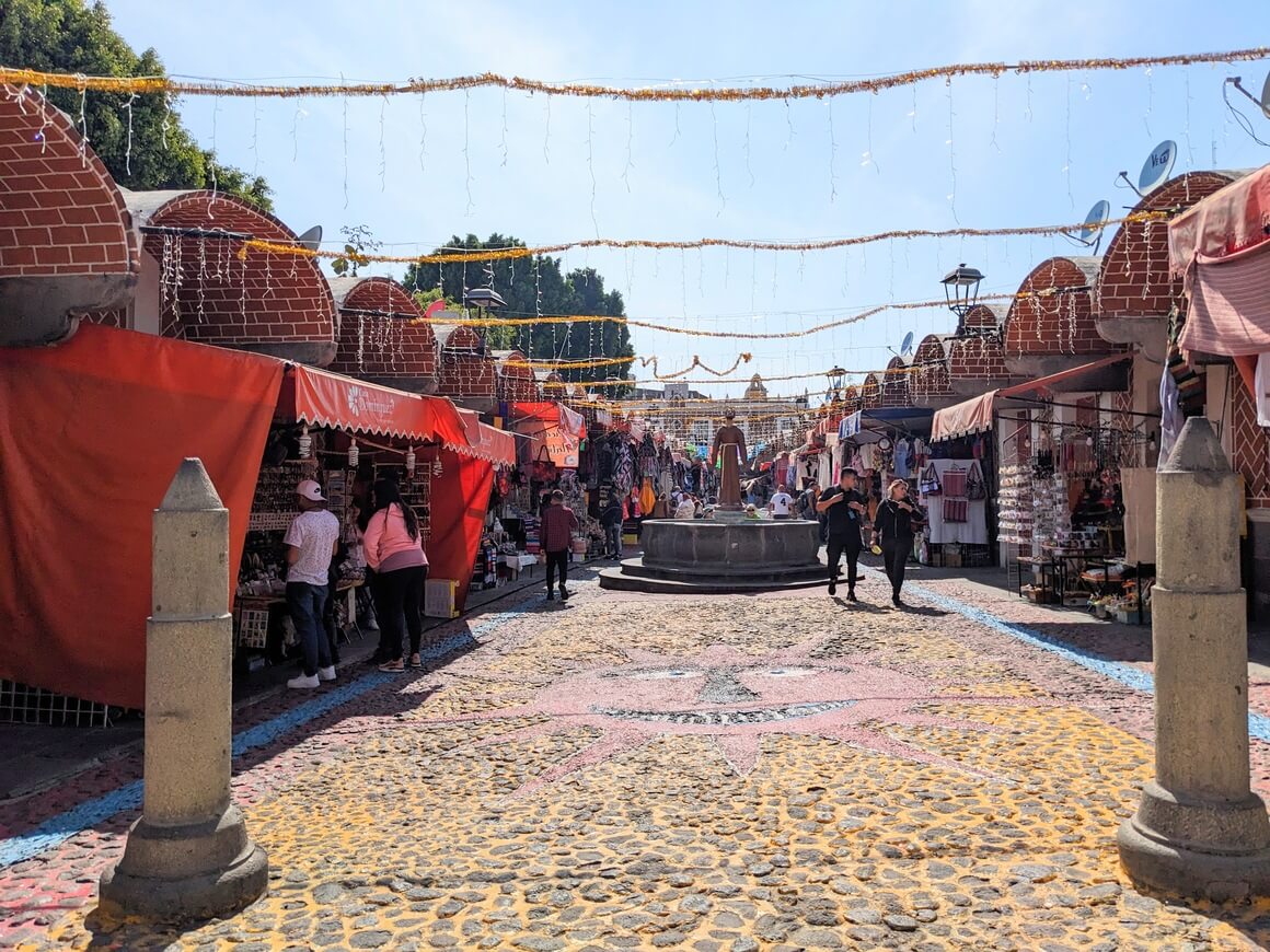 Red market stands on a cobbled street decorated with lights and tinsel 