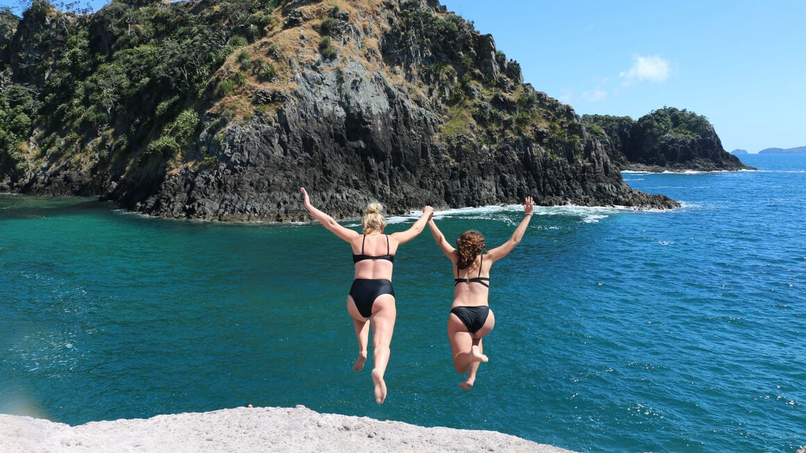 dani and friend rock jumping into crayfish bay in the coromandel, new zealand