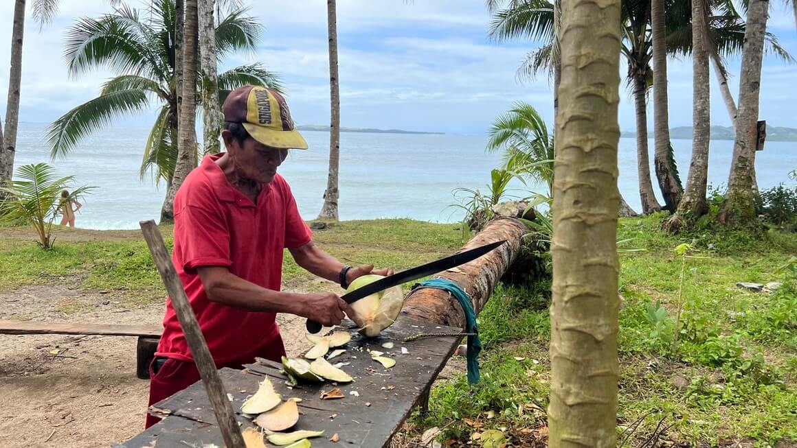 Man opening coconut on the beach in Siargao, Philippines