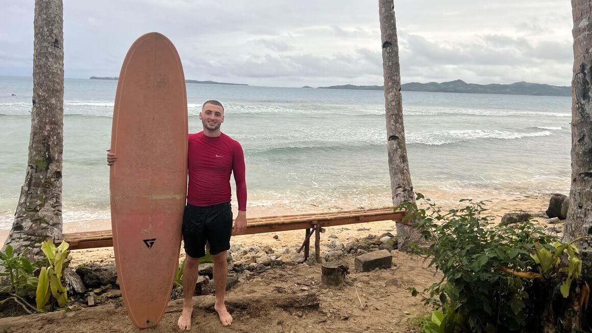 Joe with a surfboard in Siargao, Philippines