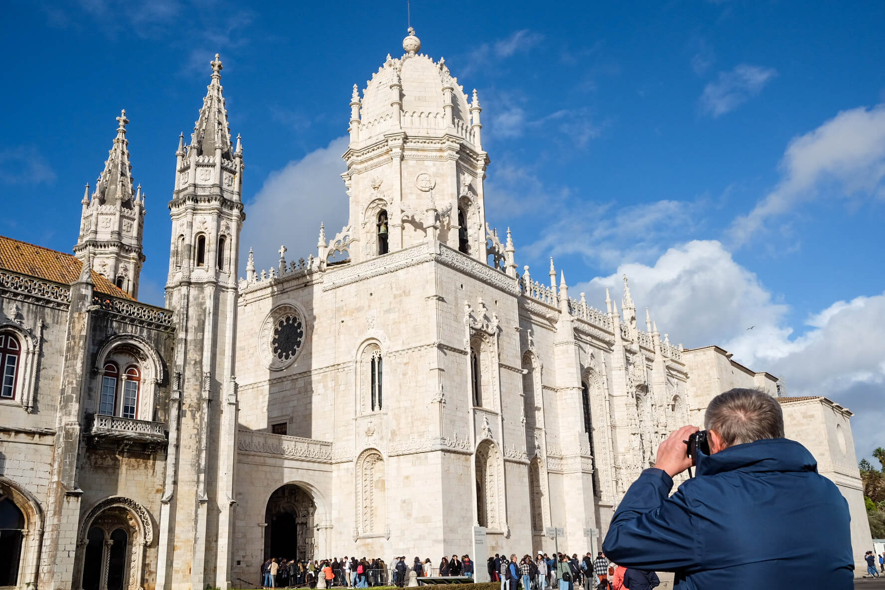 tourist with a camera takes a photo of the mosteiro dos jerónimos in belém,  lisbon, portugal