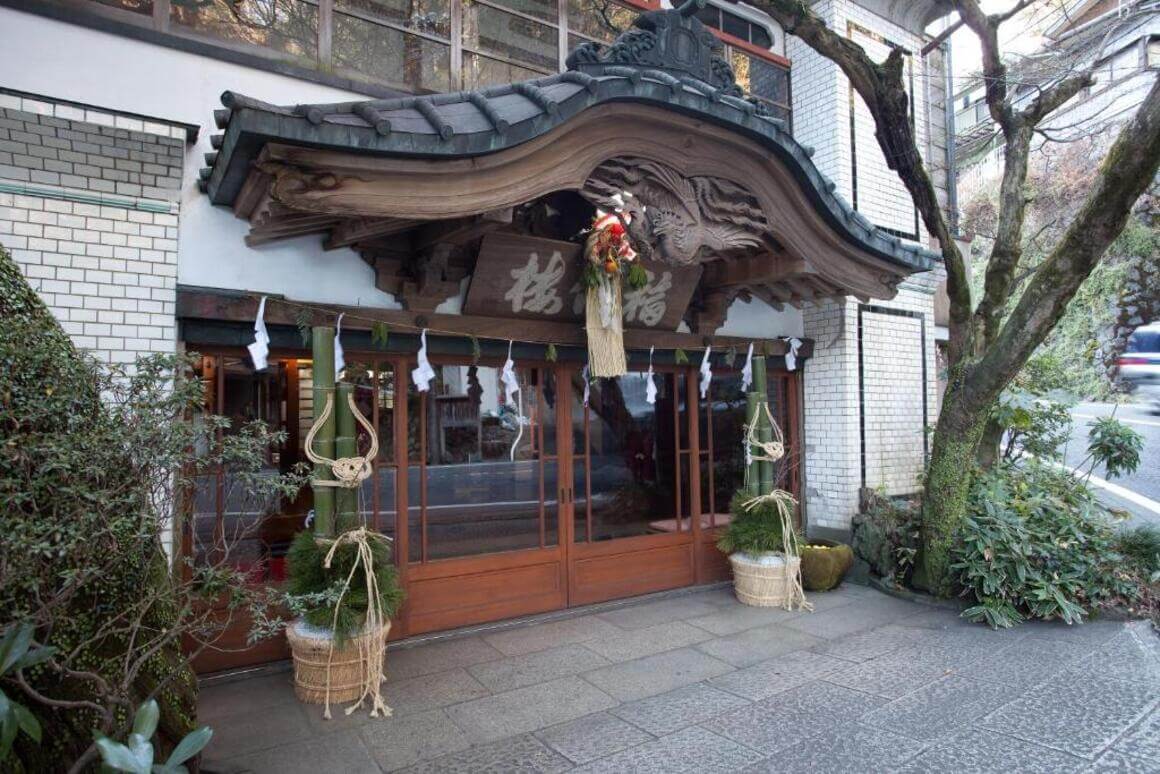 Entrance of Fukuzumiro Ryokan, Hakone with a tiled roof and a golden dragon statue on top