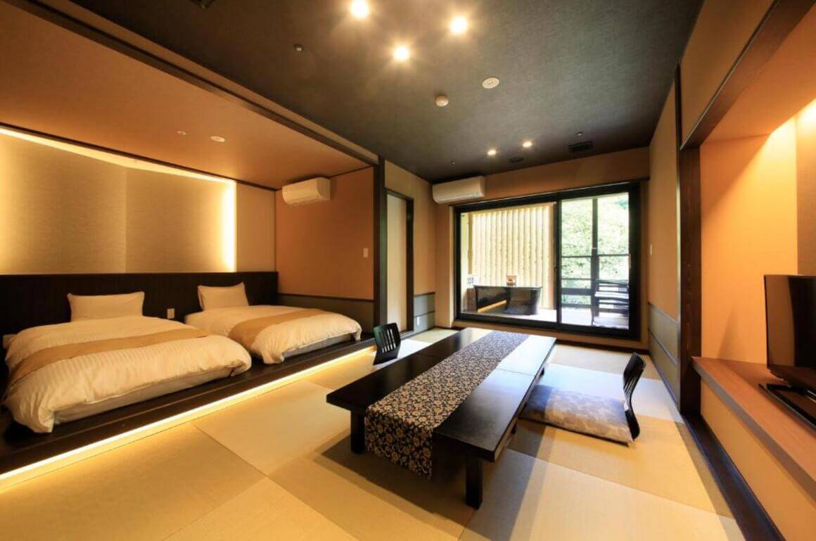A spacious bedroom in a Hakone ryokan with two white futons, a seating area, and a balcony