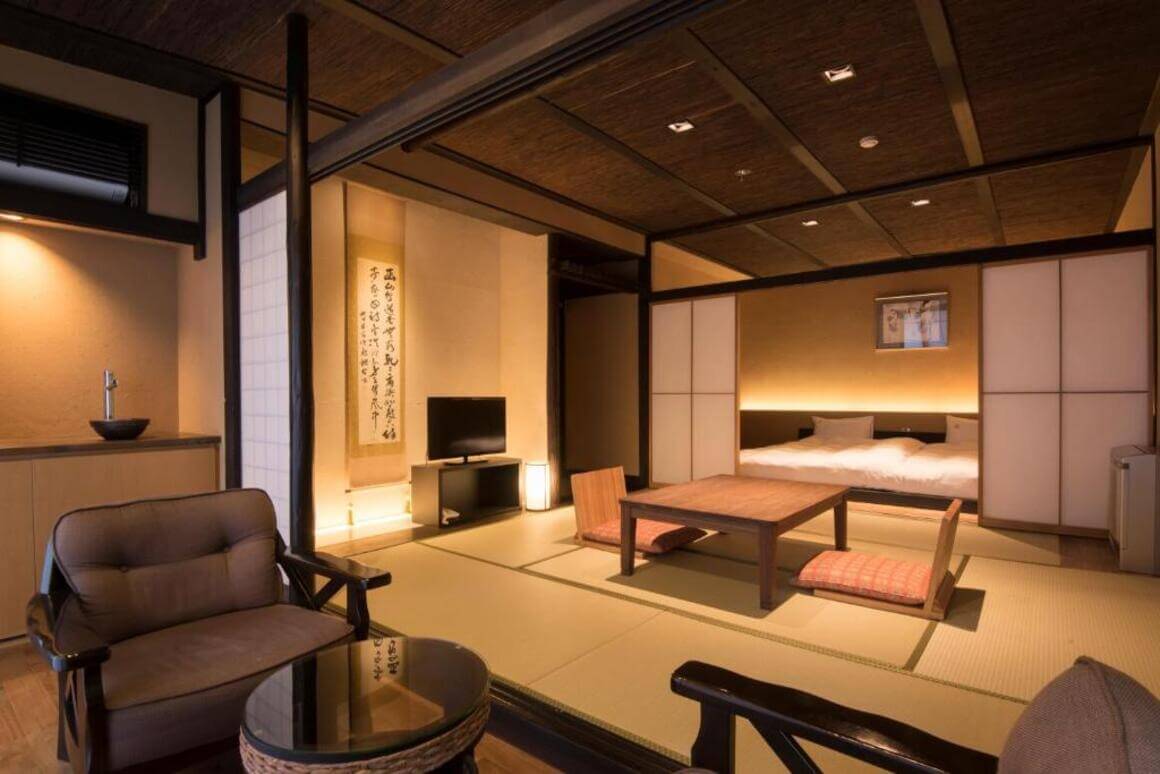  balcony with seating area overlooking a softly lit bedroom in a ryokan, complete with a wooden table and chairs, and a bed