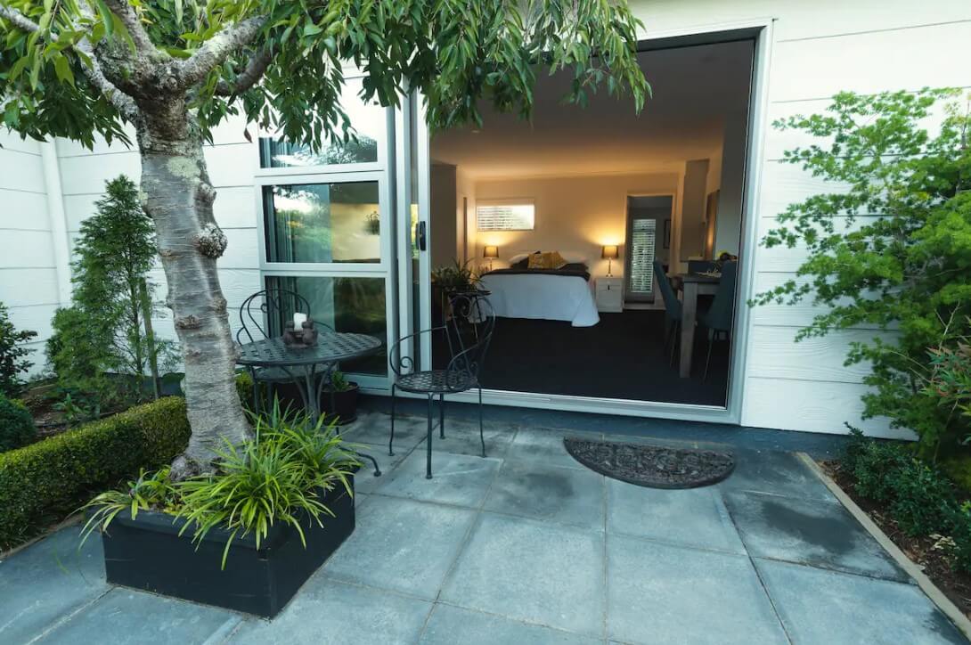 A patio with a seating area and a tree leading to spacious room in Richmond, New Zealand 