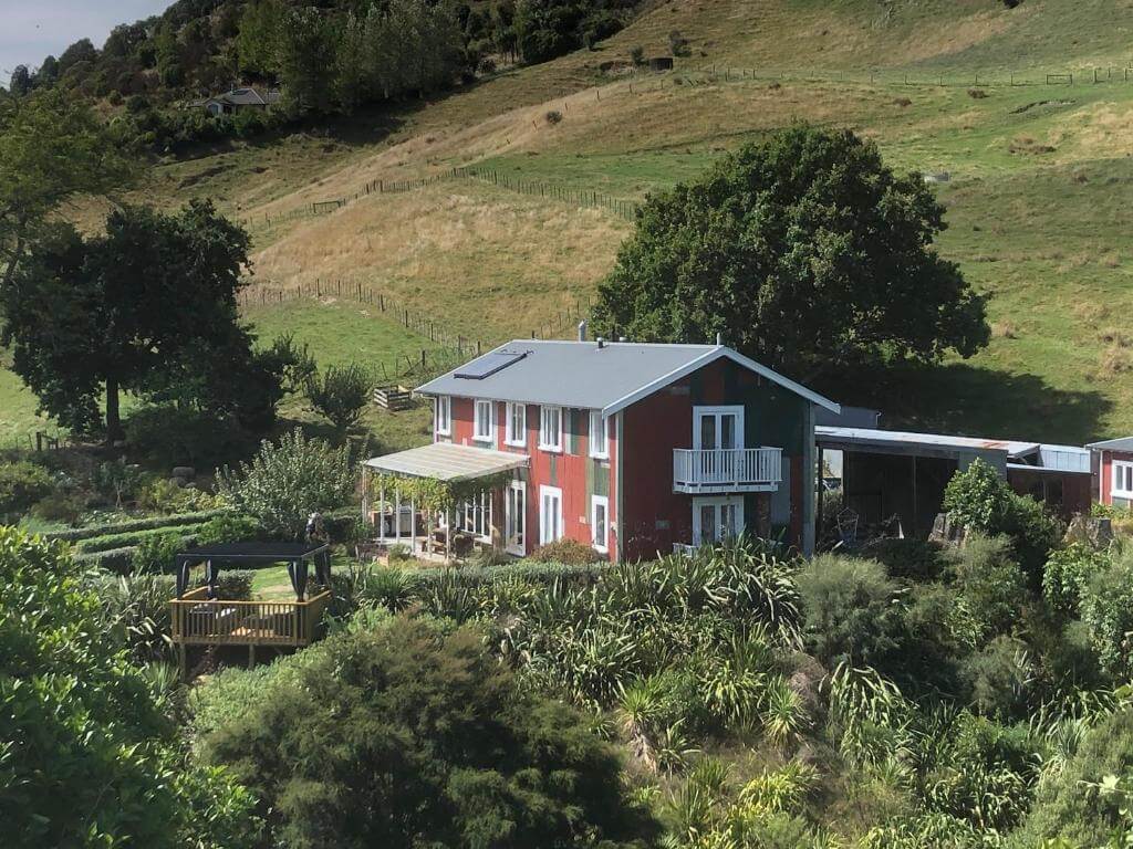 A red house standing alone in a lush grassy field in Richmond, New Zealand.