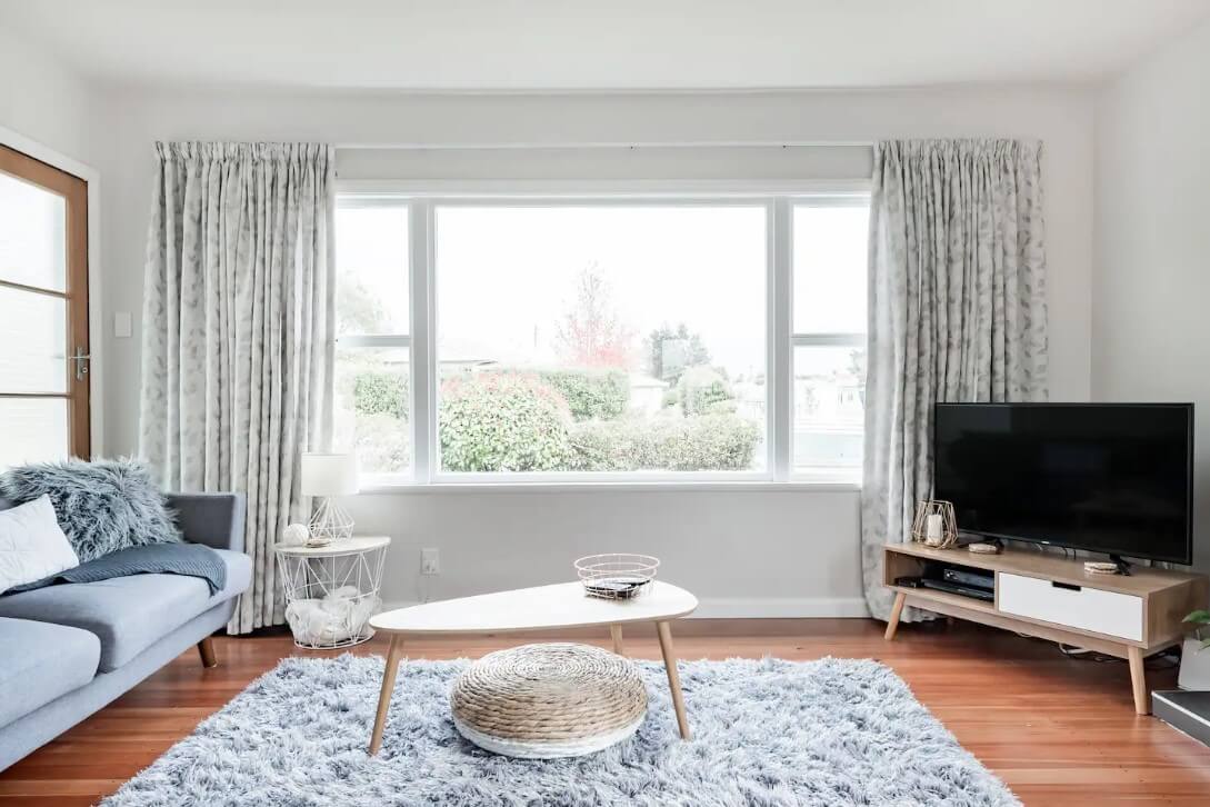 Sunny living room interior with modern furniture and a big window and white curtains