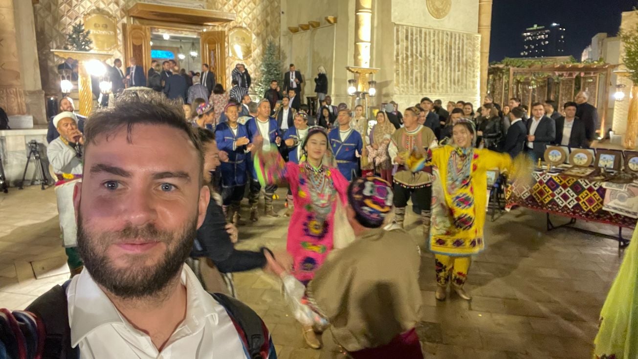 man takes a selfie with a group of dancers in Samarkand, uzbekistan
