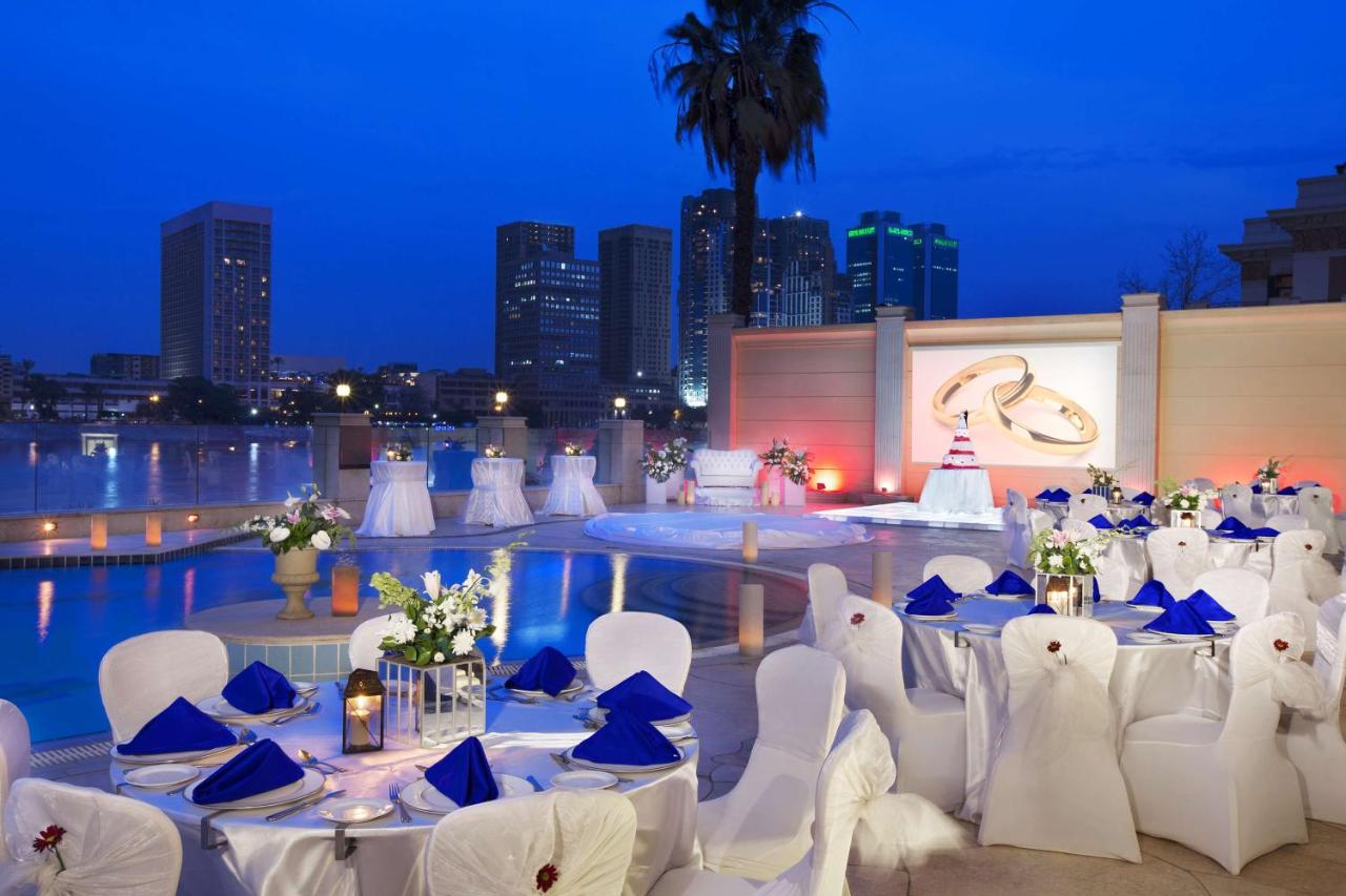 Where to stay in Cairo, at the Hilton Cairo Zamalek Residences. An image of tables set for dinner around the pool. 