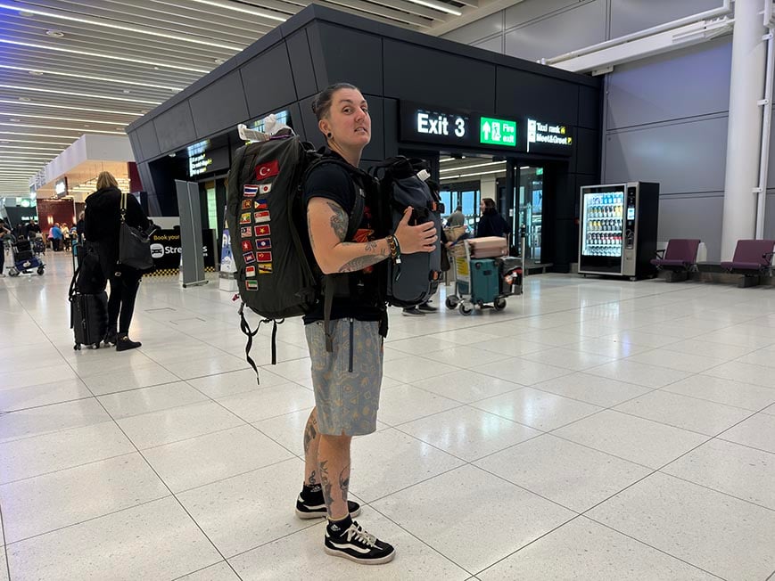 Nic wearing their backpack in the airport backpacking.