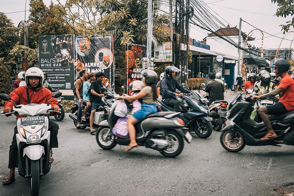 A busy intersection in Canggu in Bali. Multiple lanes of bikes are crossing paths.