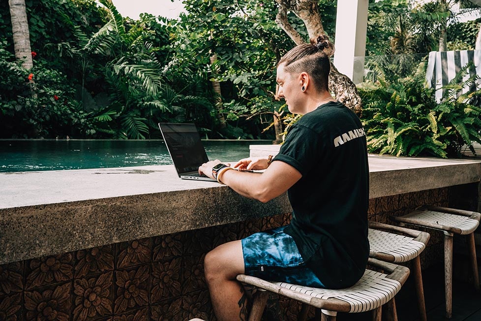 Nic working on their laptop next to the pool