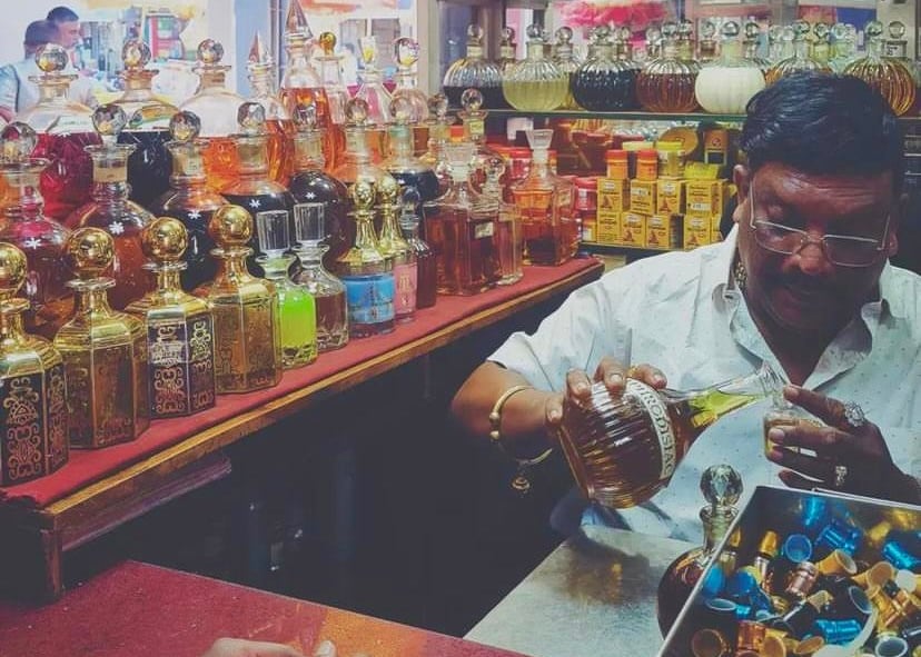 Man pouring perfume into a bottle in a tiny hop full of colourful bottles