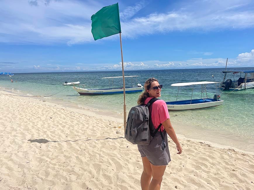 Dani with a backpack on tubud beach in siquijor, the philippines