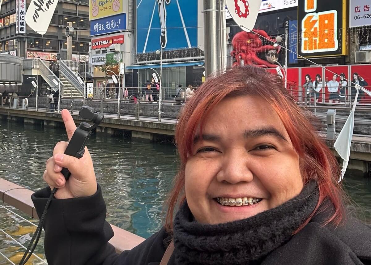 Rhenzy smiling and pointing at the train station in Namba 