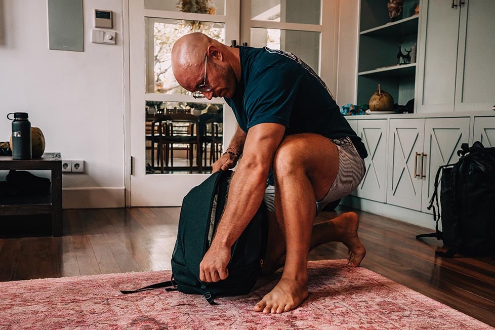 A man unzipping the large front duffel style zip on the Nemo Vantage backpack.