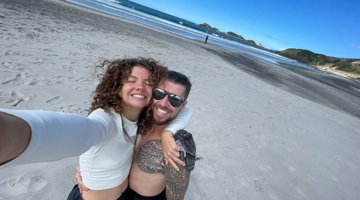 Audy and Will hugging on a beach in New Zealand