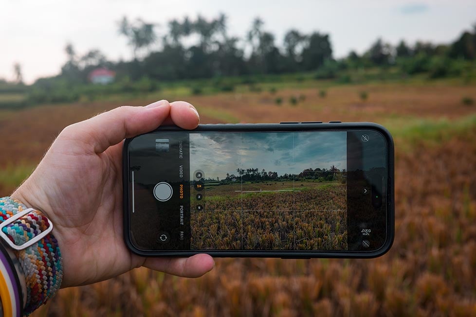 Photographer capturing a lush valley scene with their smartphone.