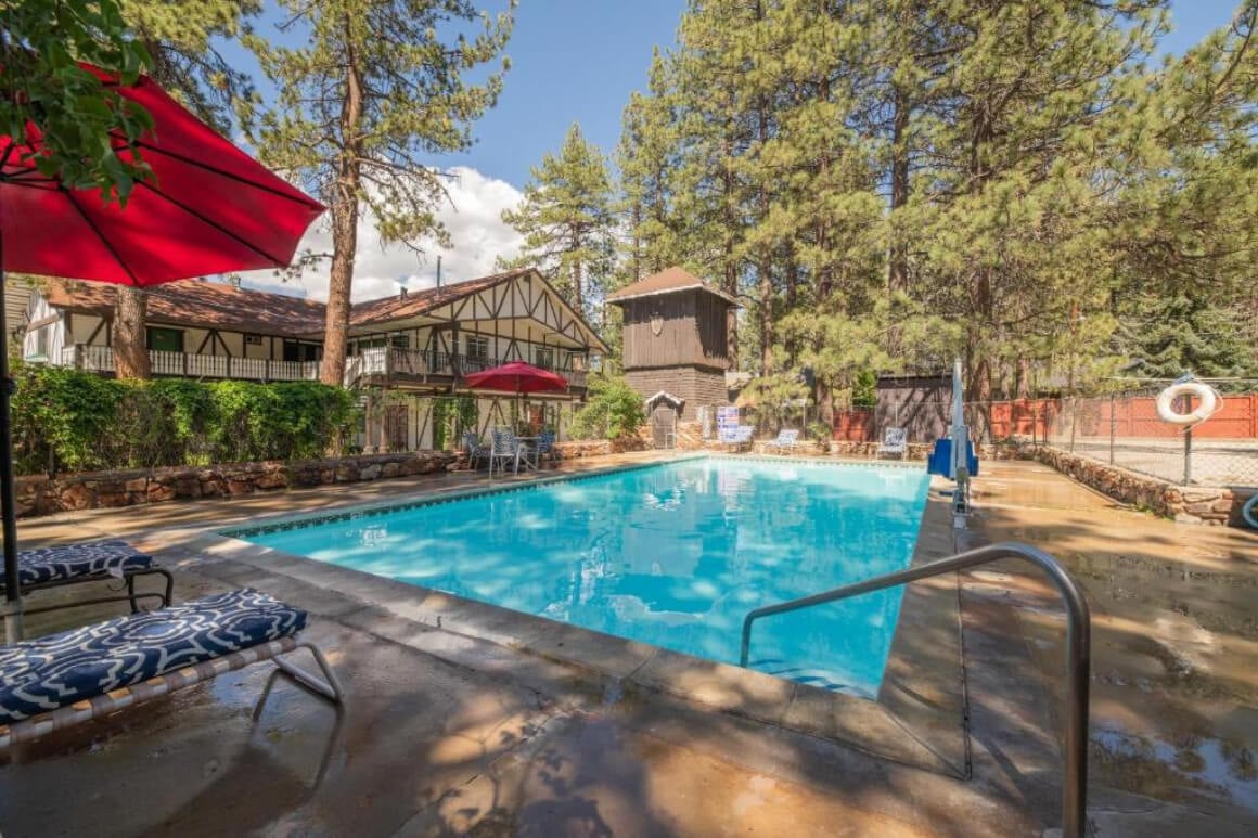 Pool area in the sunshine at Black Forest Lodge, Big Bear CA. Red umbrellas and sun loungers