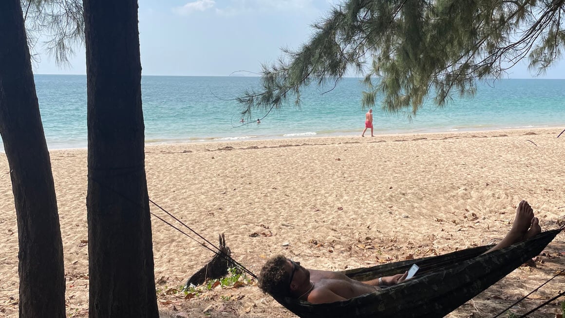harvey in a hammock between the trees, on a beach in thailand