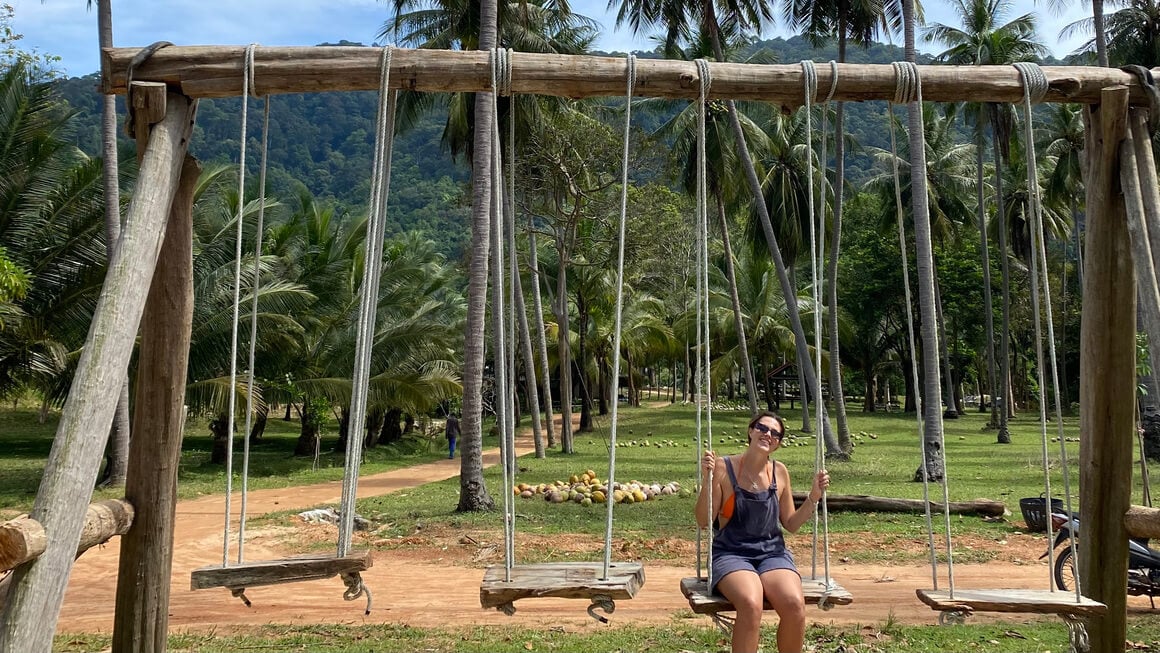 dani on a swing set by the beach in thailand