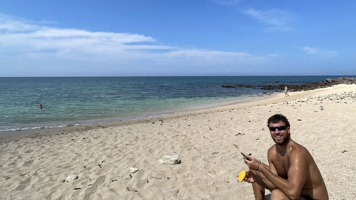 harvey eating a mango on a beach in thailand