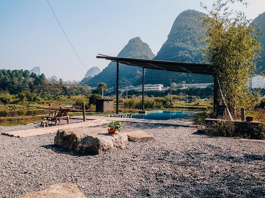 Sudder street hostel in Yangshuo, a view of the outdoor pool and garden with mountains in the background.