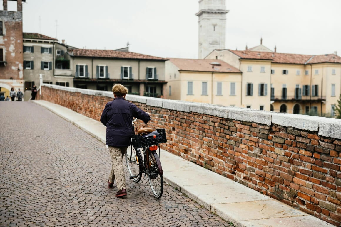 women pushing a bike over a bridge in Verona, Italy