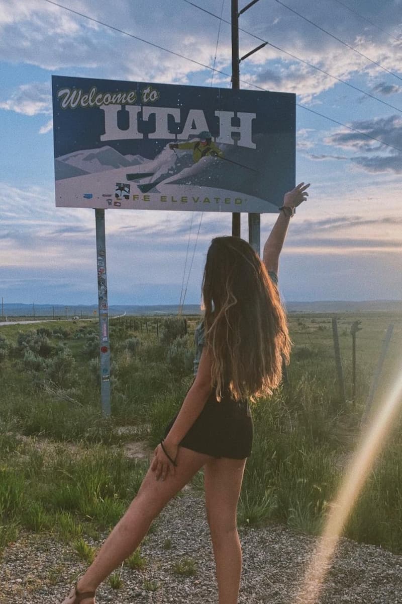 amanda standing in front of the 'welcome to utah' sign in the united states