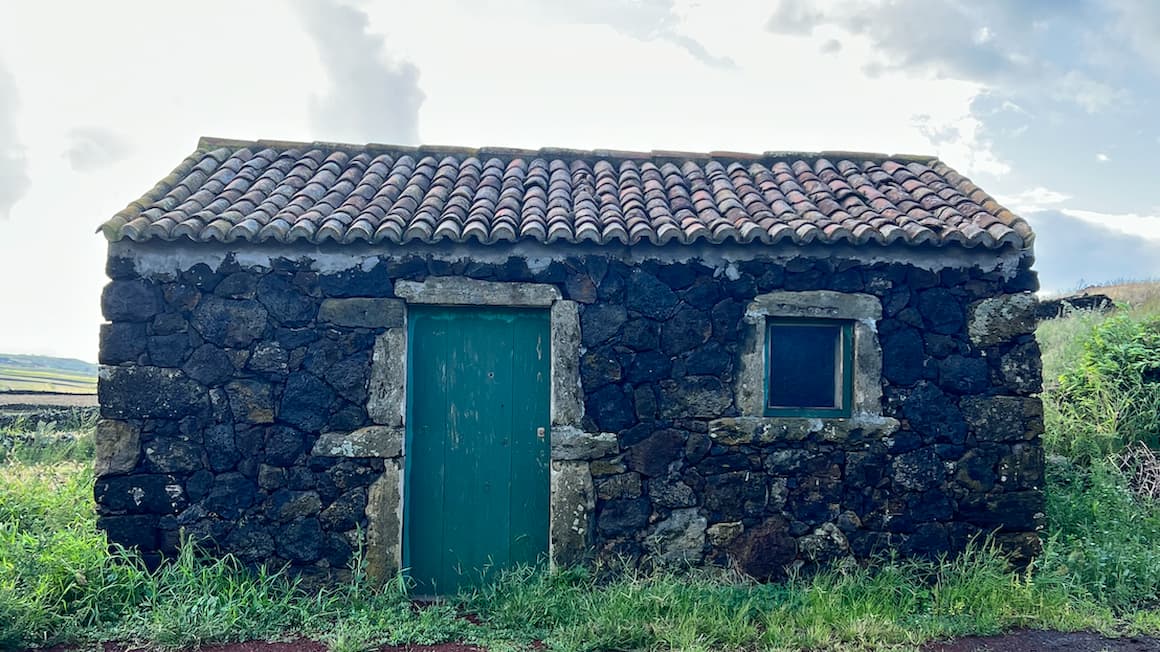 a small brick wall cottage with an aqua blue door, in the azores, portugal 