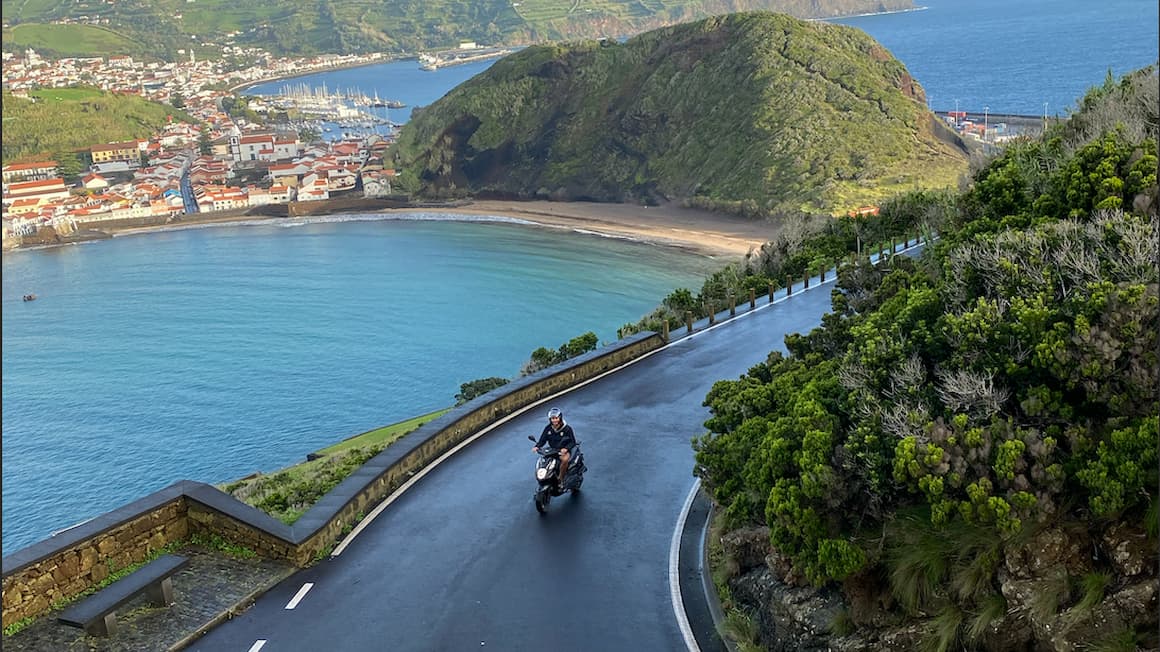 a guy riding a scooter on a windy road near the ocean in faial island, the azores, portugal 
