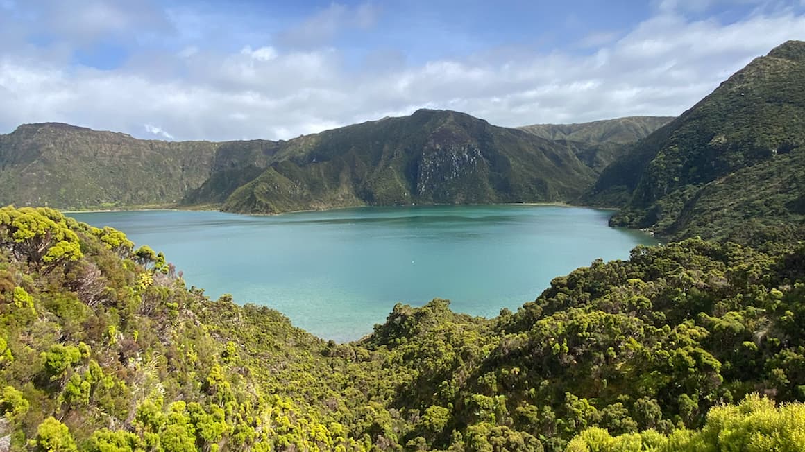 a light blue lake surrounded by lush green mountains in sao miguel island, the azores, portugal