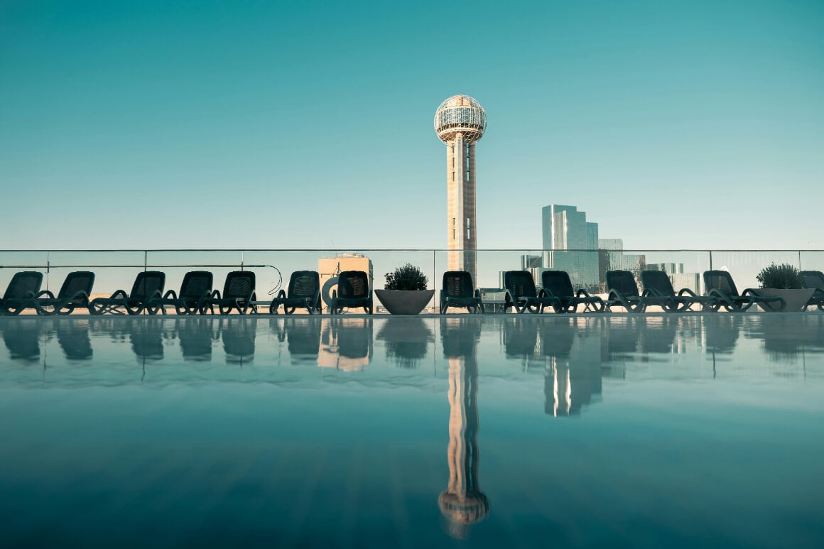 deck chairs by a pool with views of the reunion tower in downtown dallas
