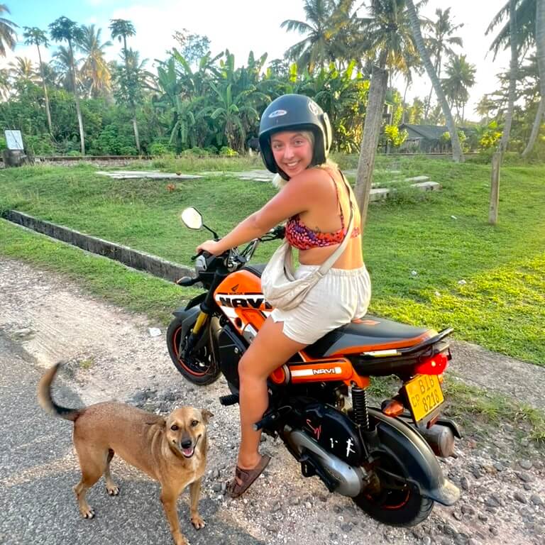 Taya posing on a motorbike with a smiling dog on the South Coast of Sri Lanka