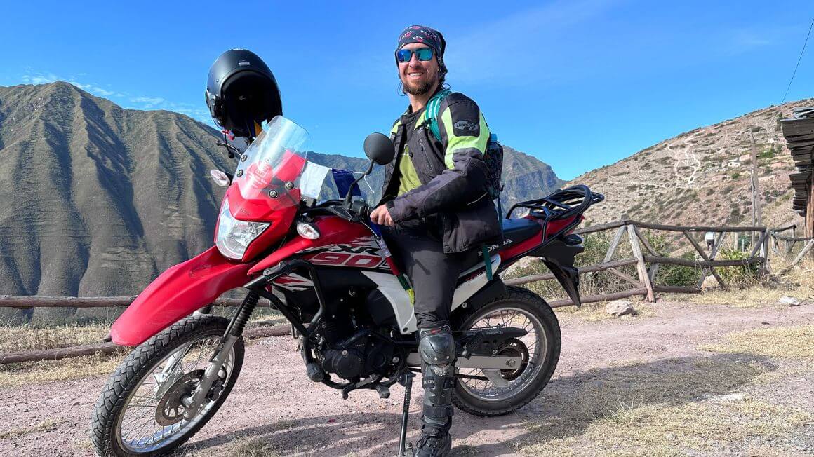 Will on a motorbike high above a town below with jungle covered mountains in the background