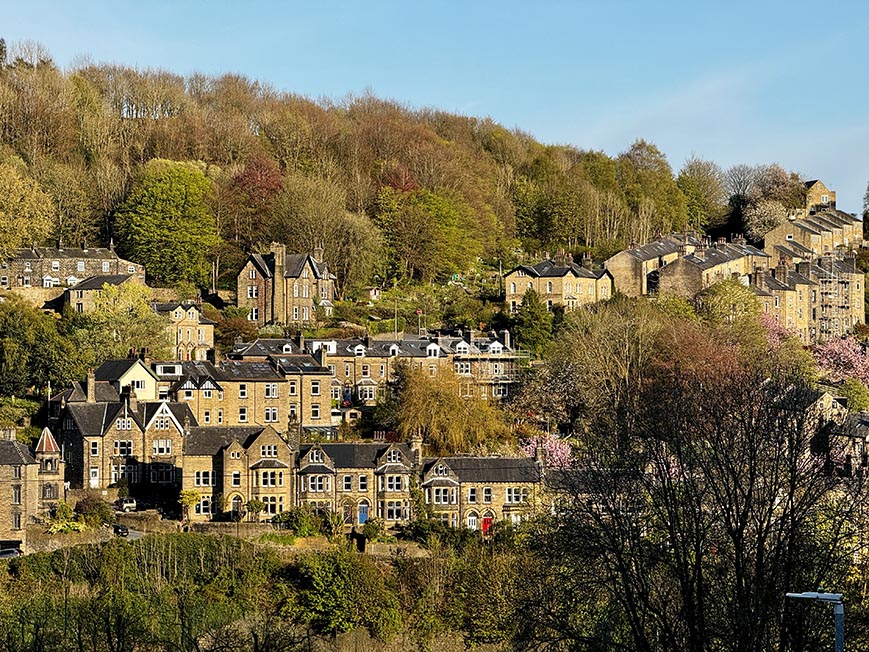 Looking out over a selection of stone built cottages and terrace houses built on a hillside in Hebden Bridge, Yorkshire. English Village