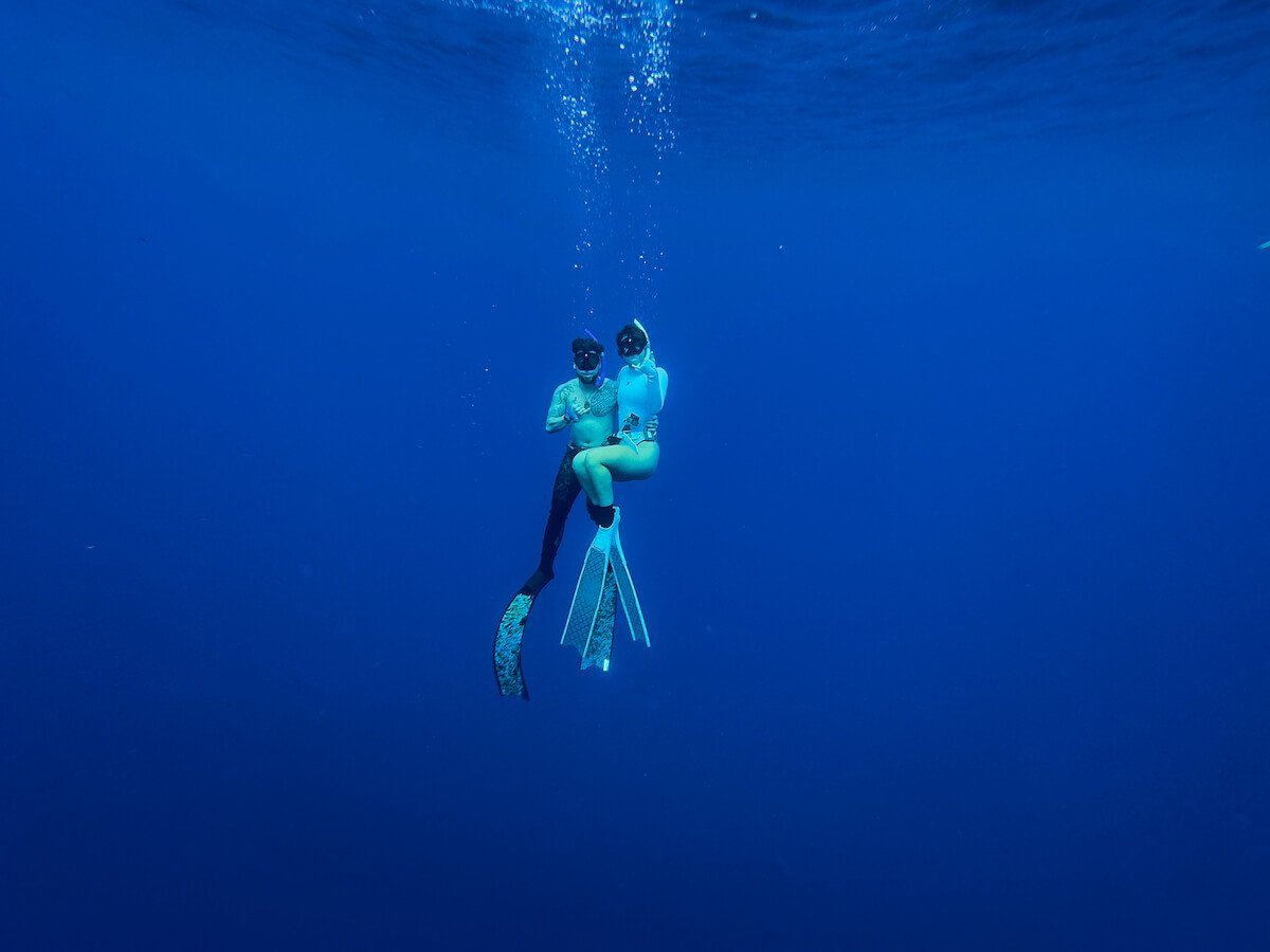 will and audy under bright blue water while freediving with rurutu whales in french polynesia
