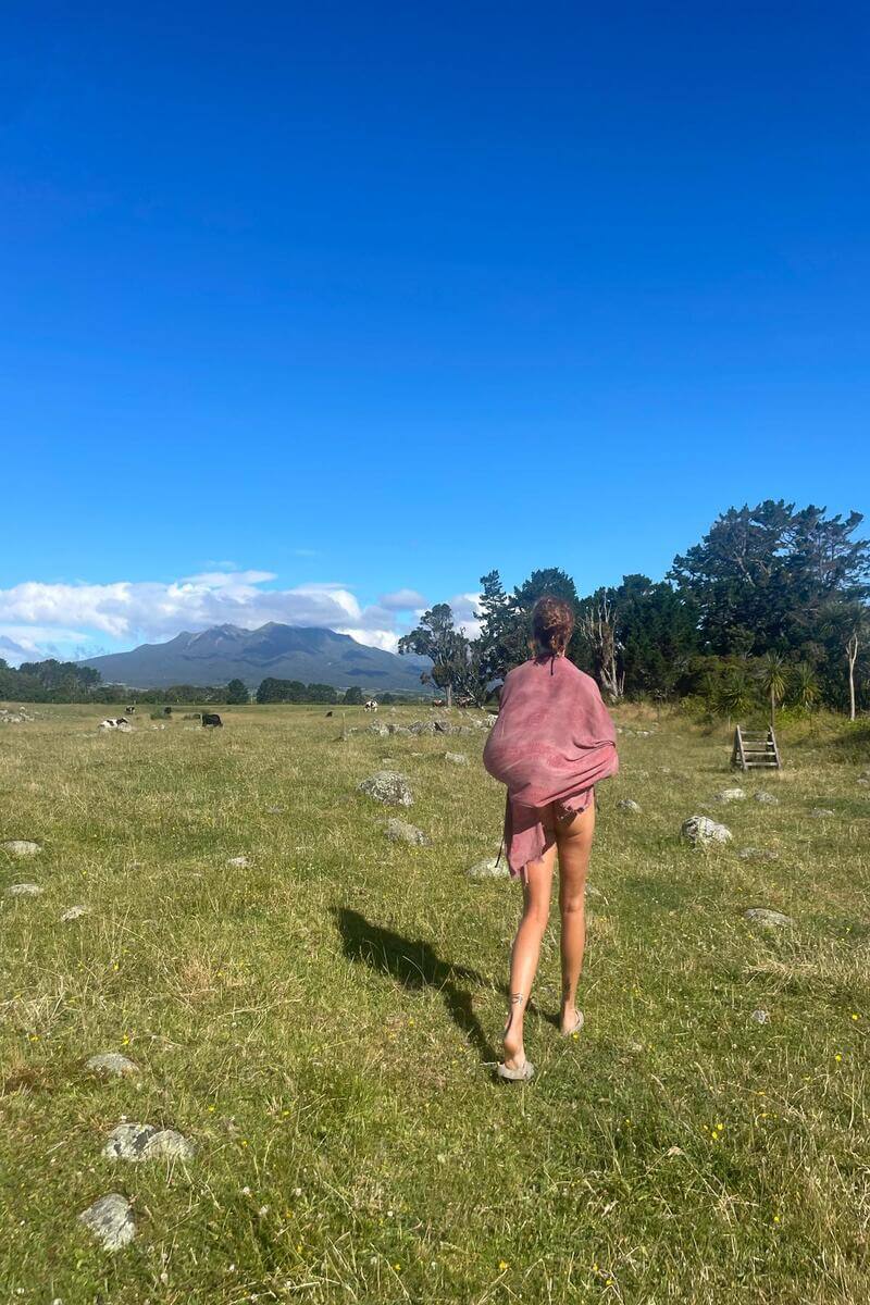 Maria walking across a paddock to get to a river for a swim in Taranaki, New Zealand
