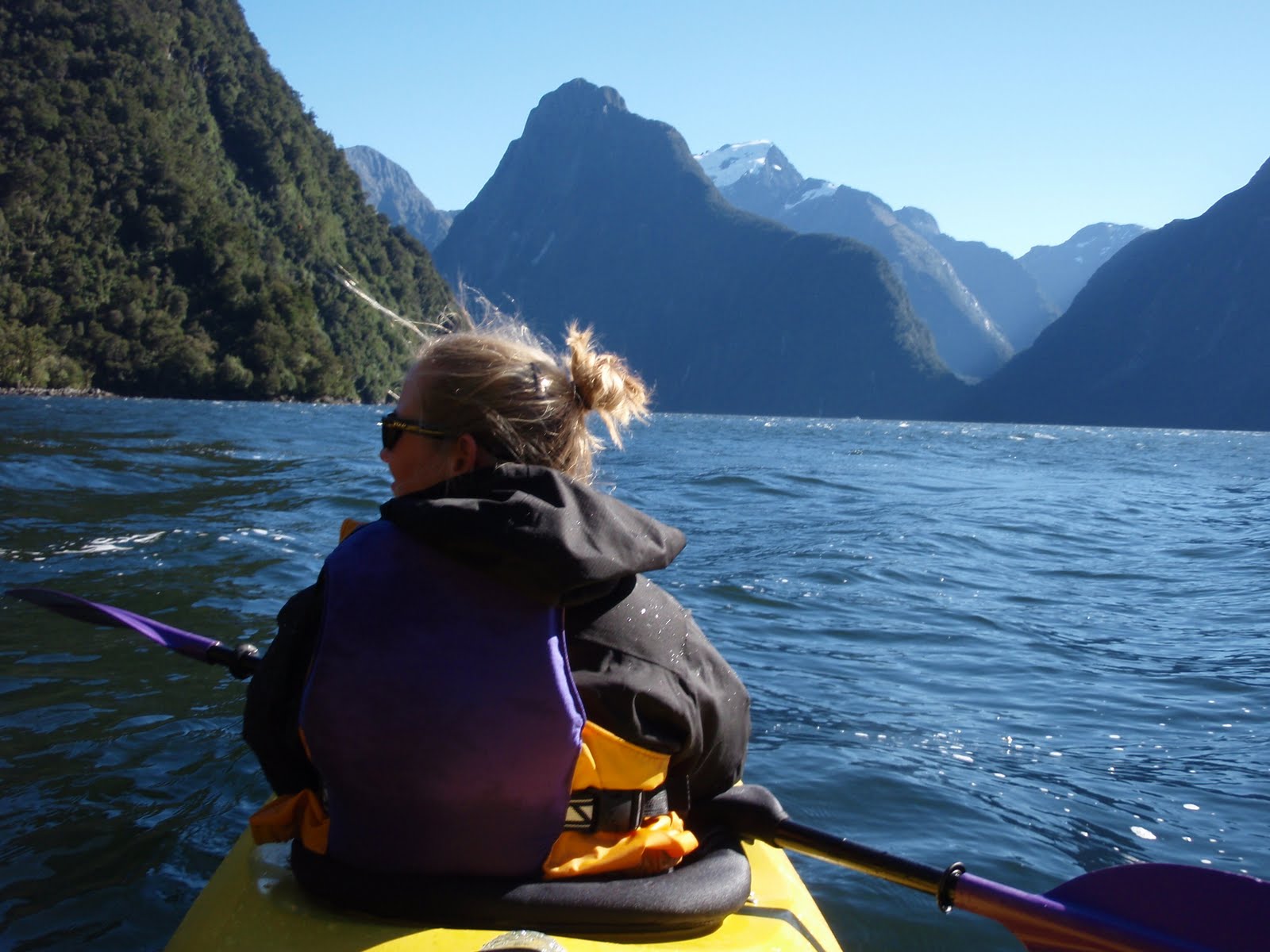 Woman kayaking on Milford Sound, New Zealand. Beautiful mountains in the background