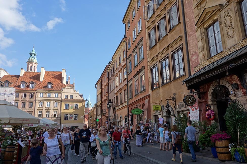 lots of people and tourists walking in the old city of warsaw poland in the summer