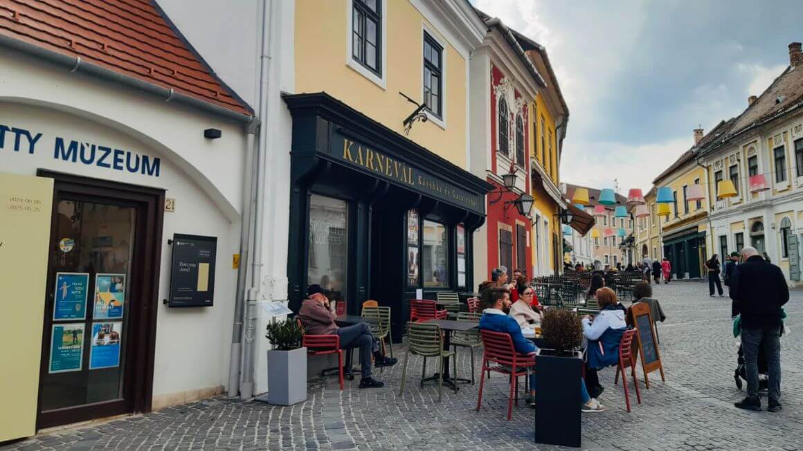 people eating outside on a cobblestone street in szentendre